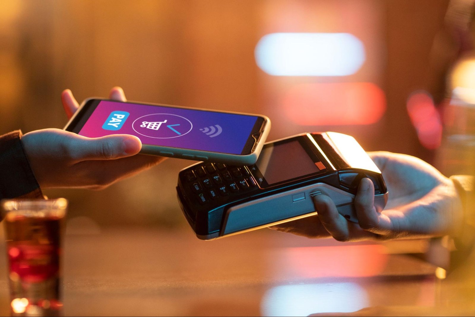 Person making a digital payment using smartphone over POS terminal, illustrating ecommerce payment gateway setup.